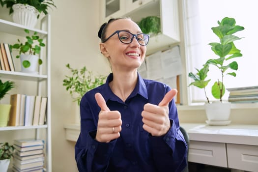 Webcam view of smiling woman showing thumbs up ok sign. Female blogger vlogger recording video, business lady during video chat conference call, teacher mentor giving online lesson, filming training course