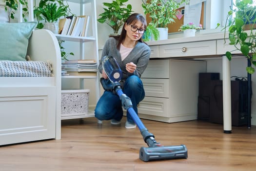 Middle aged female doing vacuuming at home. Cleanliness, routine house cleaning, home hygiene, housecleaning, housekeeping, housework concept