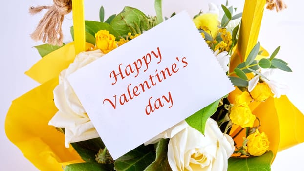 Happy Valentine's day text on a white leaf on a bouquet of bright beautiful flowers