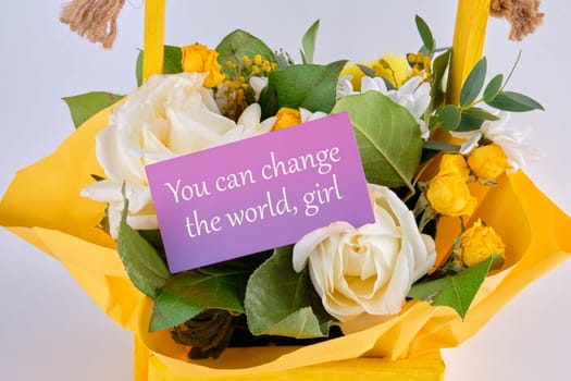 You can change the world, girl text written on a business card in a basket with blooming flowers