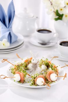 Appetizer quail egg stuffed with alfalfa sprouts with a slice of salmon, on a wooden skewer. Buffet serving for the Easter table.