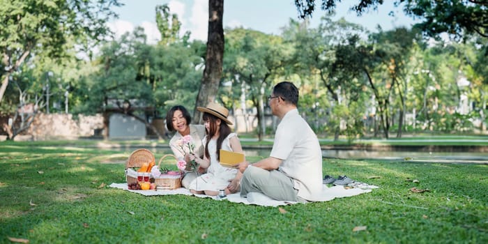 Family day, family picnic together at the park. Retired grandparent take granddaughter to relax and spend time together at the park.