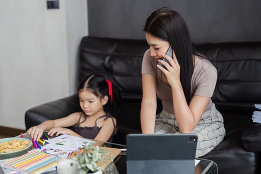 Businessman working at home. working woman talk on mobile and working on tablet and take care of her daughter during summer.