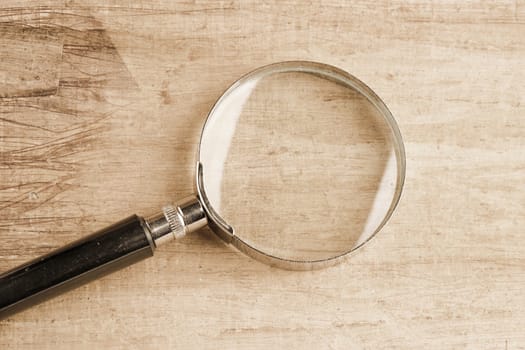 A magnifying glass lying against a vintage background