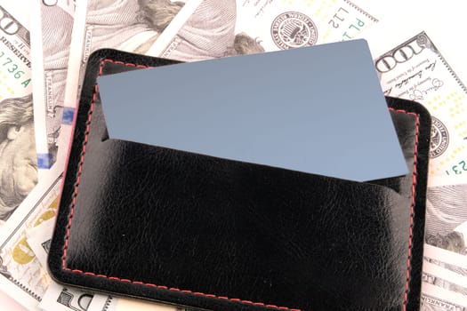 A business card with a place to write sticks out of the wallet against the background of money