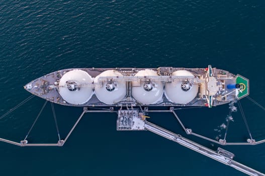 Aerial of Liquified Natural Gas LNG carrier moored to a small gas terminal. Fuel crisis. Sanctions. Top down shot.