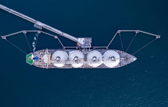 Aerial of Liquified Natural Gas LNG carrier moored to a small gas terminal. Fuel crisis. Sanctions. Top down shot.