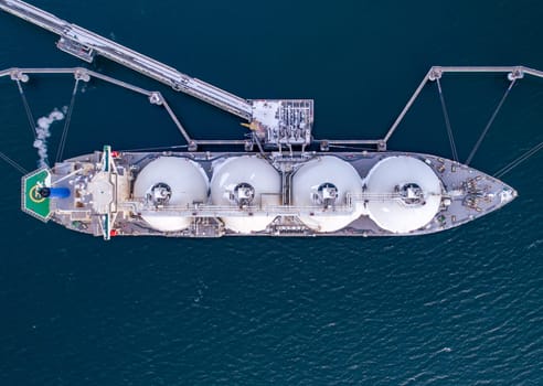 Aerial of Liquified Natural Gas LNG carrier moored to a small gas terminal. Fuel crisis. Sanctions. Top down shot.