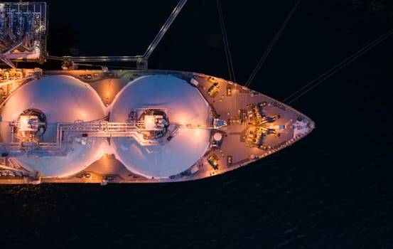 Aerial of Liquified Natural Gas LNG carrier moored to a small gas terminal. Fuel crisis. Sanctions. Top down view of a ship bow
