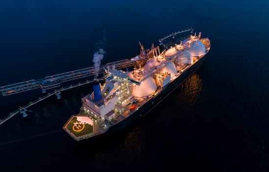 Aerial of Liquified Natural Gas LNG carrier moored to a small gas terminal at dusk. Fuel crisis. Sanctions.