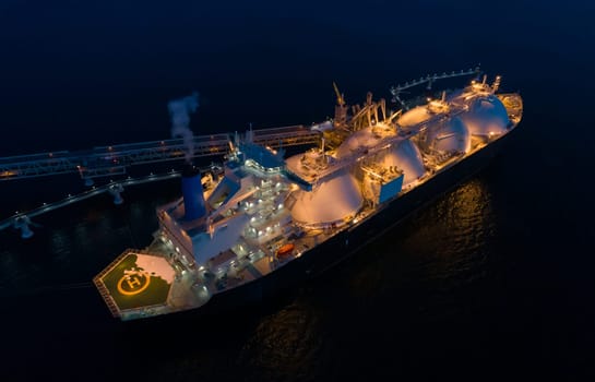 Aerial of Liquified Natural Gas LNG carrier moored to a small gas terminal at dusk. Fuel crisis. Sanctions.