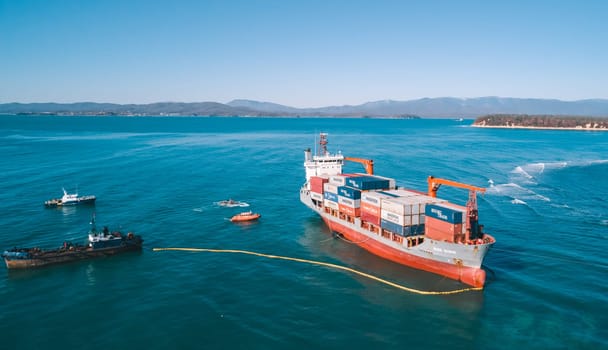 Aerial view of a RISE SHINE container cargo ship stands aground after a storm with floating boom around the ship to prevent the spread of petroleum. Container ship ran aground during the storm.