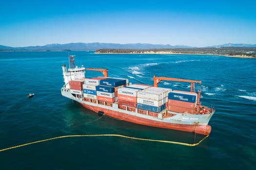 Aerial view of a RISE SHINE container cargo ship stands aground after a storm with floating boom around the ship to prevent the spread of petroleum. Container ship ran aground during the storm.