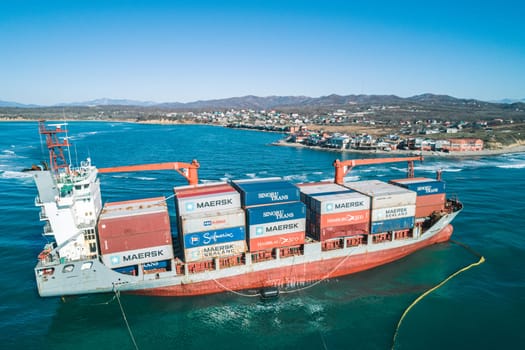 Aerial view of a RISE SHINE container cargo ship stands aground after a storm with floating boom around the ship to prevent the spread of petroleum. Container ship ran aground during the storm.