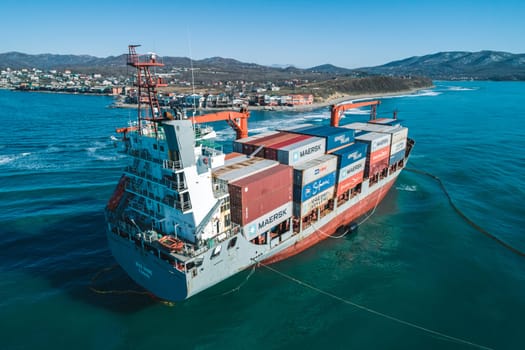Aerial view of a RISE SHINE container cargo ship stands aground after a storm with floating boom around the ship to prevent the spread of petroleum. Container ship ran aground during the storm.