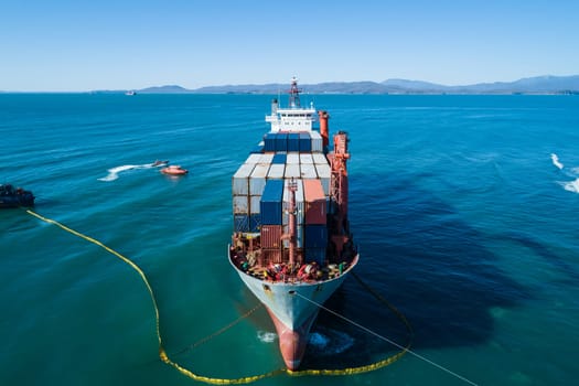 Aerial view of a RISE SHINE container cargo ship stands aground after a storm with floating boom around the ship to prevent the spread of petroleum. Container ship ran aground during the storm.