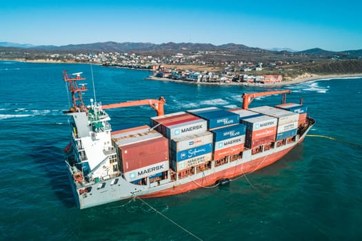 Aerial view of a RISE SHINE container cargo ship stands aground after a storm with floating boom around the ship to prevent the spread of petroleum. Container ship ran aground during the storm.