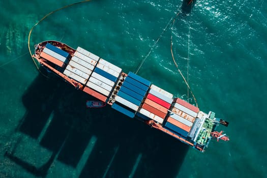 Aerial top down view of a container cargo ship stands aground after a storm with floating boom around the ship to prevent the spread of petroleum..