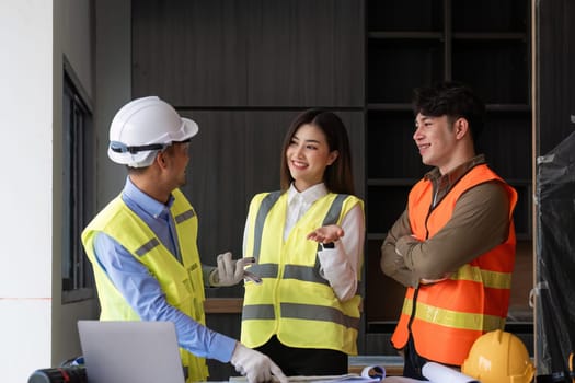 civil engineers meet to plan a construction project and brainstorm ideas about how to work through paper plans and records with laptop