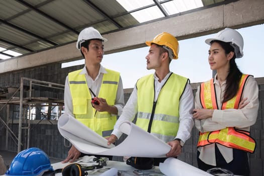 team of civil engineers and architects wearing hard hats Currently in a brainstorming meeting holding project plans to plan a building construction project..