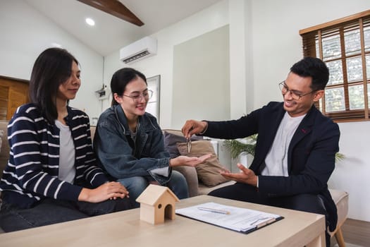 Asian couple looking at house plans and talking with a real estate agent about signing documents for purchase of a new home..