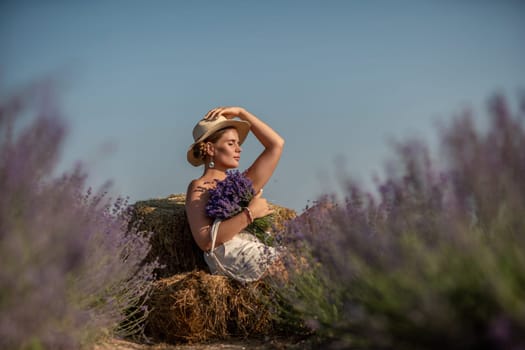 A woman is sitting in a field of lavender flowers and wearing a straw hat. She is smiling and holding a bouquet of flowers. Scene is peaceful and serene, as the woman is surrounded by the beauty of nature.