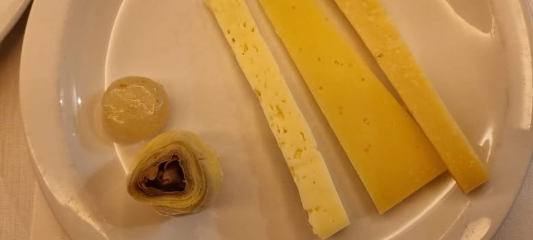 Top-down view of gourmet cheese slices with figs on a white plate