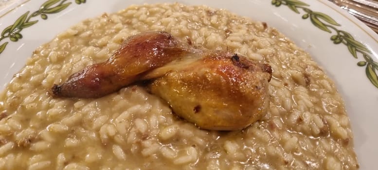 Close-up of creamy risotto with a succulent roasted chicken leg on a decorative plate