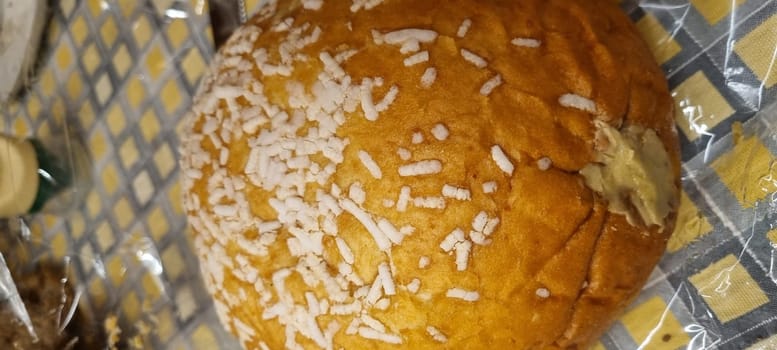 Close-up shot of a golden coconut bun with a sprinkling of coconut shavings