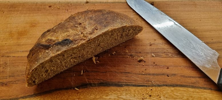 Close-up of a rustic artisan bread loaf sliced on a wooden cutting board next to a knife