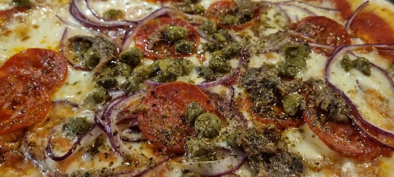 Close-up of a delicious gourmet italian pizza with cheese. Tomatoes. Onions. And olives. Freshly made and baked. Showcasing the traditional homemade dough and flavorful pizza toppings