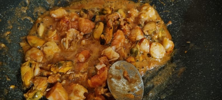 Close-up of a delightful mix of shellfish and sauce in a cooking pan