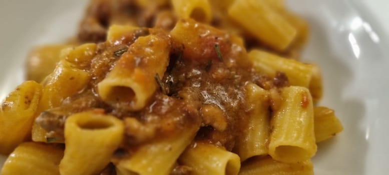 Close-up of delicious rigatoni pasta topped with rich and meaty bolognese sauce, served on a plate