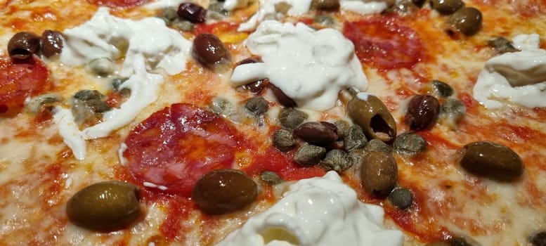 Close-up view of delicious pepperoni pizza topped with olives and dollops of mozzarella cheese