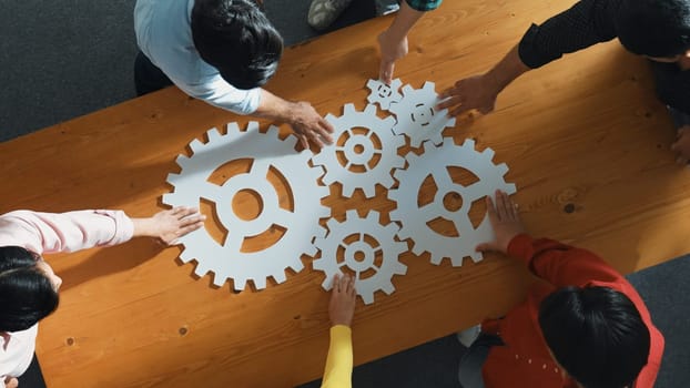 Top view of business people gathering white gear together at meeting table. Group start up team in casual cloth working together connecting cog together. Cooperate, teamwork,togetherness. Convocation.