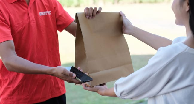 delivery man Deliver a paper bag package to the beautiful woman at the front of the house according to the order..