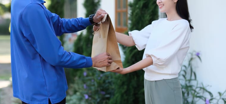 delivery man Deliver a paper bag package to the beautiful woman at the front of the house according to the order..