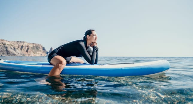 Woman sup yoga. Middle age sporty woman practising yoga pilates on paddle sup surfboard. Female stretching doing workout on sea water. Modern individual hipster outdoor summer sport activity