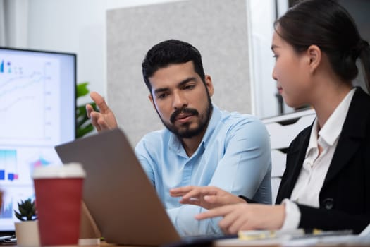 Professional Asian employee work together as team in corporate office, discussing business plans and data to achieve success on desk with laptop. Modern office worker teamwork concept. Concord