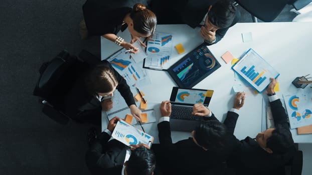 Top down aerial view of manager standing and present marketing plan to skilled investor. Diverse business team working together to analyze financial statistic graph at meeting table. Directorate.