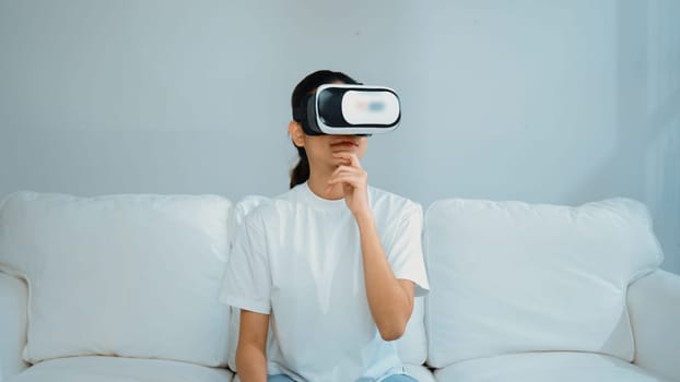 Young woman using virtual reality VR goggle at home for vivancy online shopping experience. The virtual reality VR innovation optimized for female digital entertainment lifestyle.