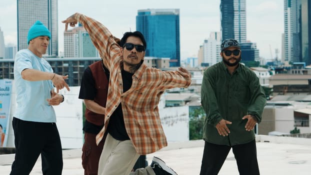 Hispanic hipster dancing surrounded by multicultural friend at city view with blue sky. Group of street dancer performing at rooftop. Active, fun, happy atmosphere. Outdoor sport 2024. Endeavor.