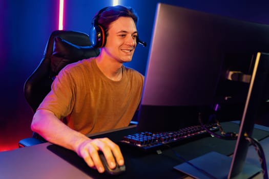 Host channel of gaming smart streamer playing online game to be winner, wearing headphone with viewers live steaming on media social online for selected team competition at neon light room. Pecuniary.