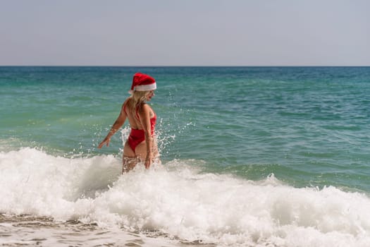 A woman in Santa hat on the seashore, dressed in a red swimsuit. New Year's celebration in a hot country.