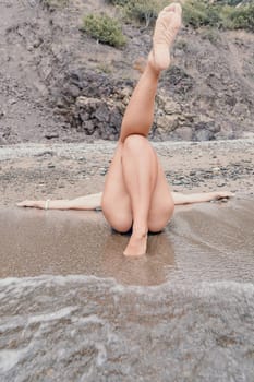 Woman travel sea. Young Happy woman in a long red dress posing on a beach near the sea on background of volcanic rocks, like in Iceland, sharing travel adventure journey