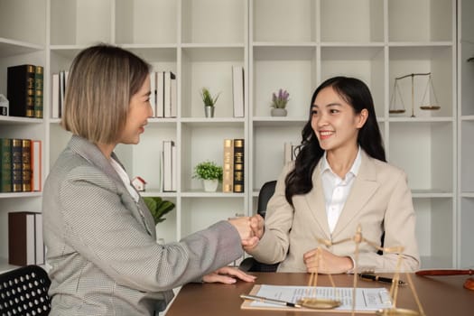 Lawyers and businesswomen shake hands and reach an agreement on cooperation contract documents. In the lawyer's office.