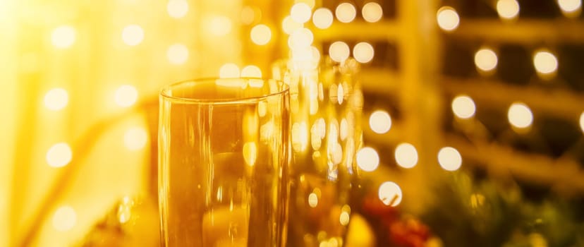 Two champagne glasses filled with champagne are placed on a table with a fruit arrangement. The glasses are surrounded by lights, creating a festive atmosphere. The table is set for a celebration or a special occasion