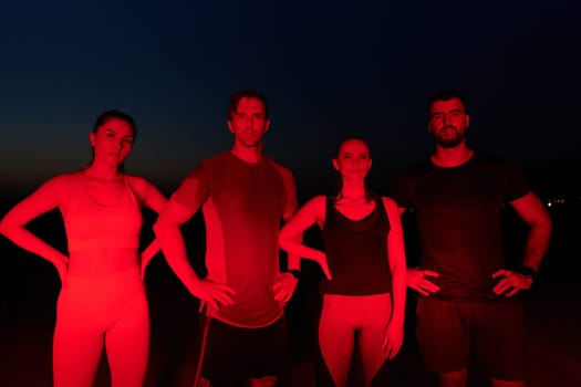 In the late-night hours, a diverse group of exhausted athletes find solace under a red glow, reflecting on their day-long marathon journey and celebrating camaraderie amidst fatigue.