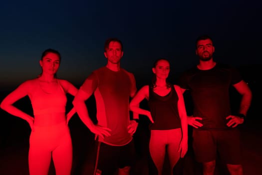 In the late-night hours, a diverse group of exhausted athletes find solace under a red glow, reflecting on their day-long marathon journey and celebrating camaraderie amidst fatigue.