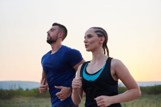 A vibrant couple dashes running the outdoors, embodying the essence of athleticism and romance, their confident strides reflecting a shared commitment to fitness and preparation for future marathon challenges.